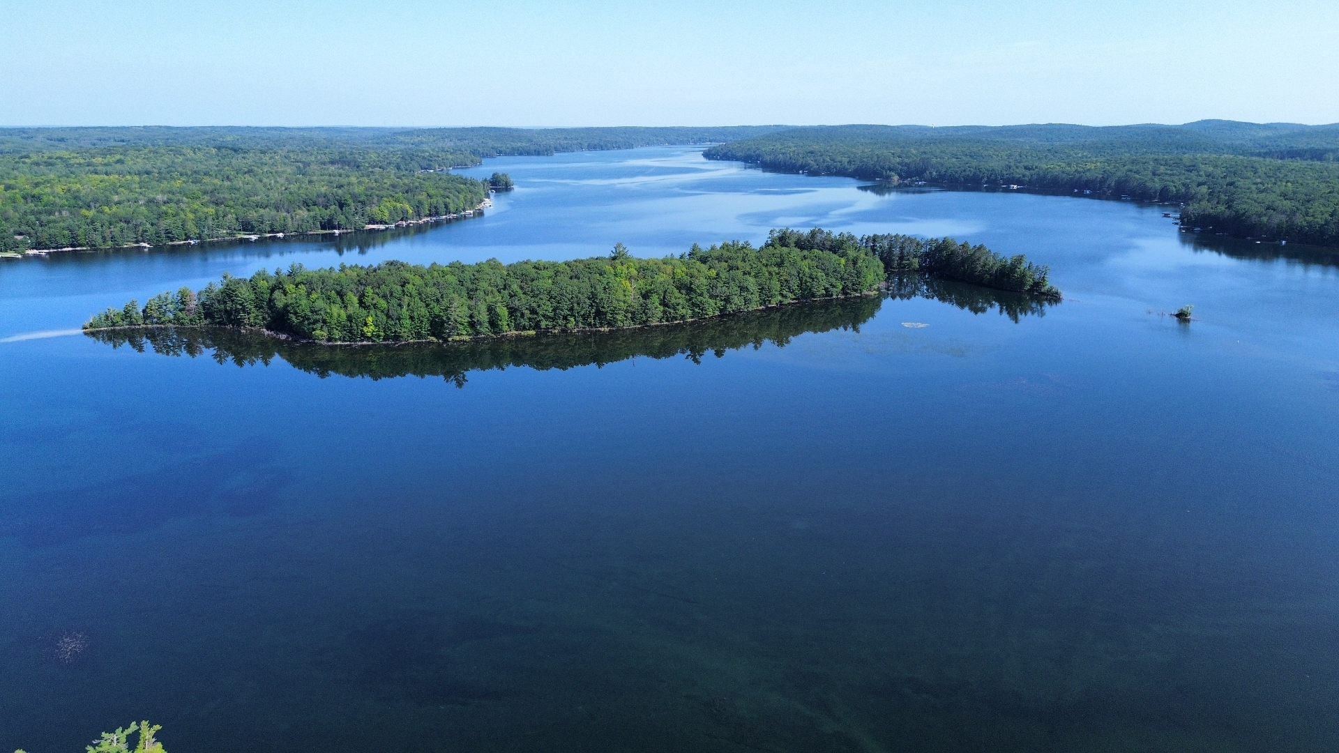 Aerial view of a broad north-woods lake with forested islands and shoreline