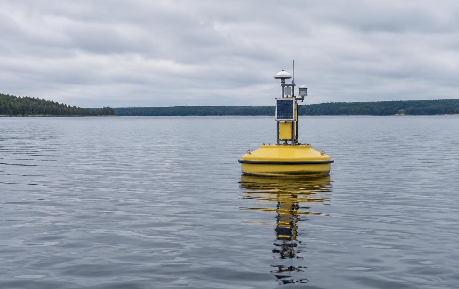 A yellow water quality monitoring buoy on open lake water