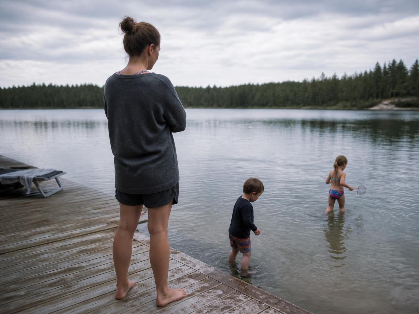 A woman standing on her dock watching her kids play in the shallow water